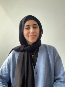 A portrait image with a woman in a headscarf smiling at the camera